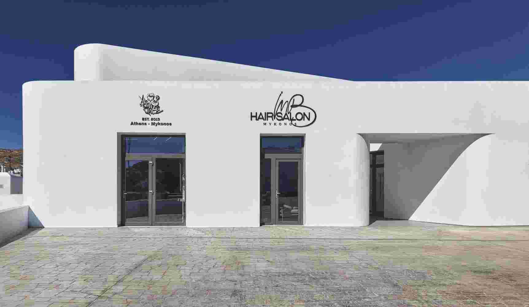 white facade with curved window openings with a background of a deep blye Mykonos sky.