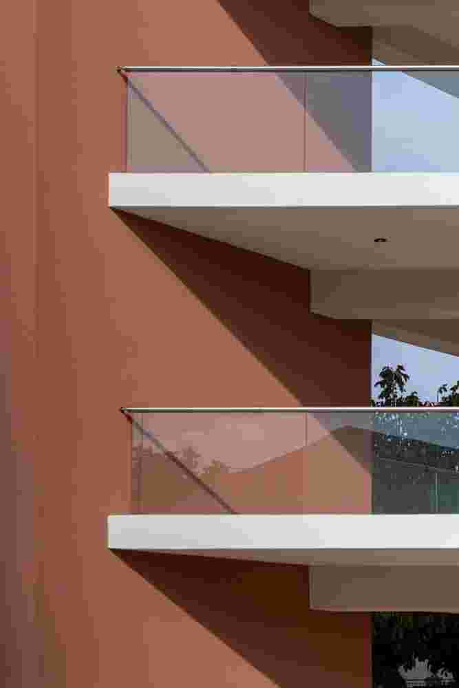 Prismatic housing facade detail in Spata with hierarchical volumes and glass balcony railings